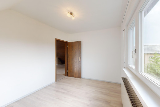 pièce vide avec radiateur, plancher de bois, et lumière naturelle