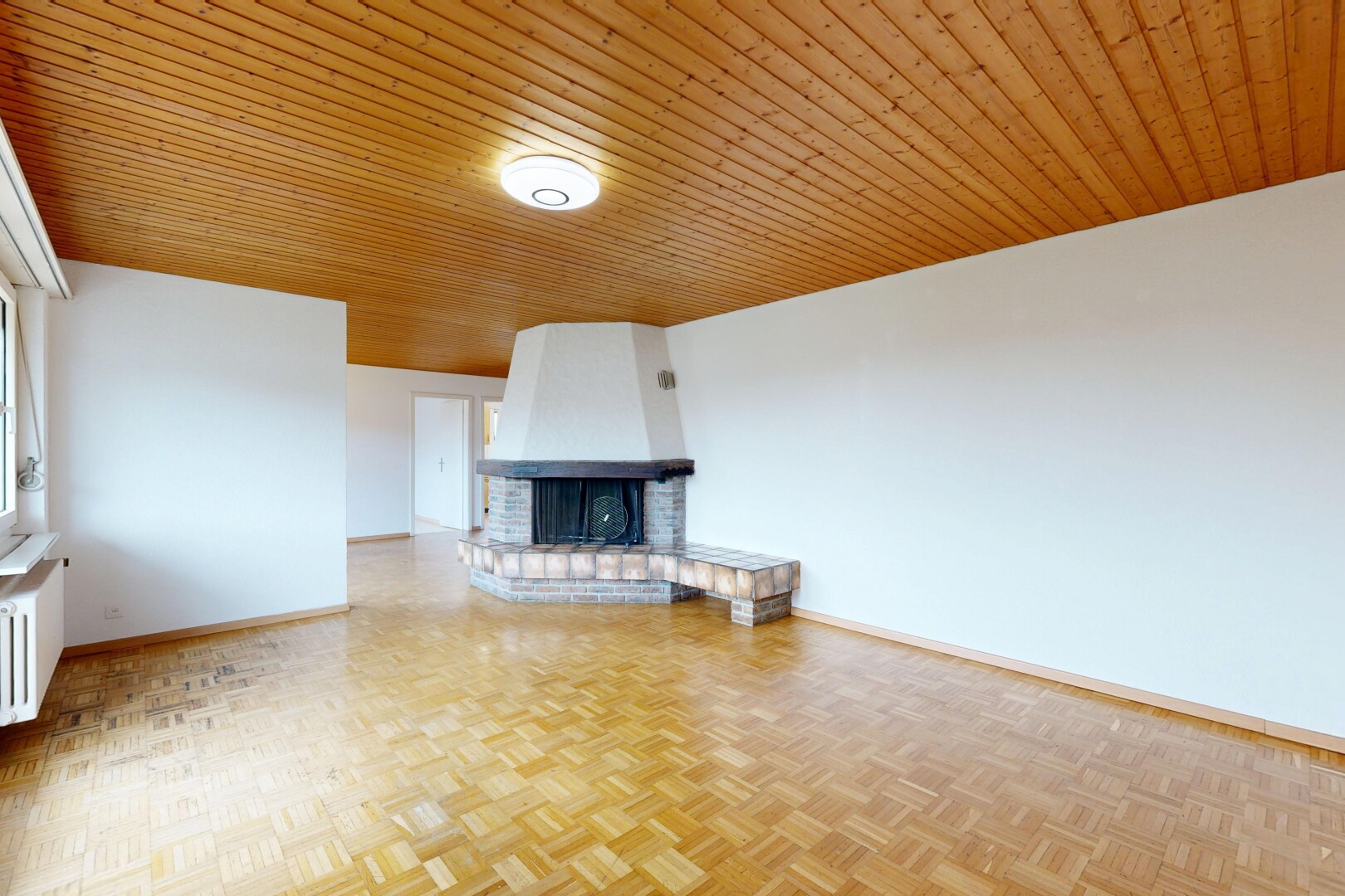 unfurnished living room with parquet flooring, a brick fireplace, wooden ceiling, and radiator heating unit