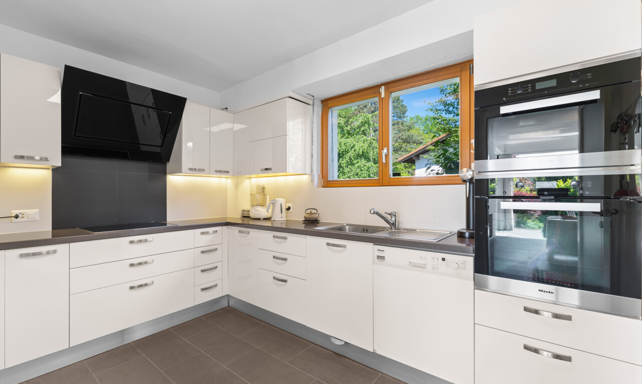 kitchen featuring stainless steel double oven, range hood, dark countertops, white cabinetry, and dishwasher