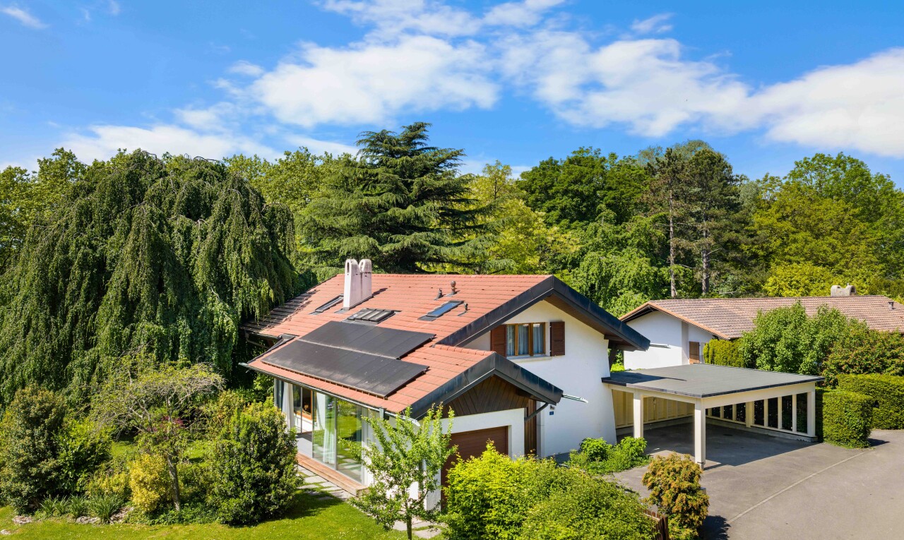 view of home featuring roof mounted solar panels, driveway, and covered porch