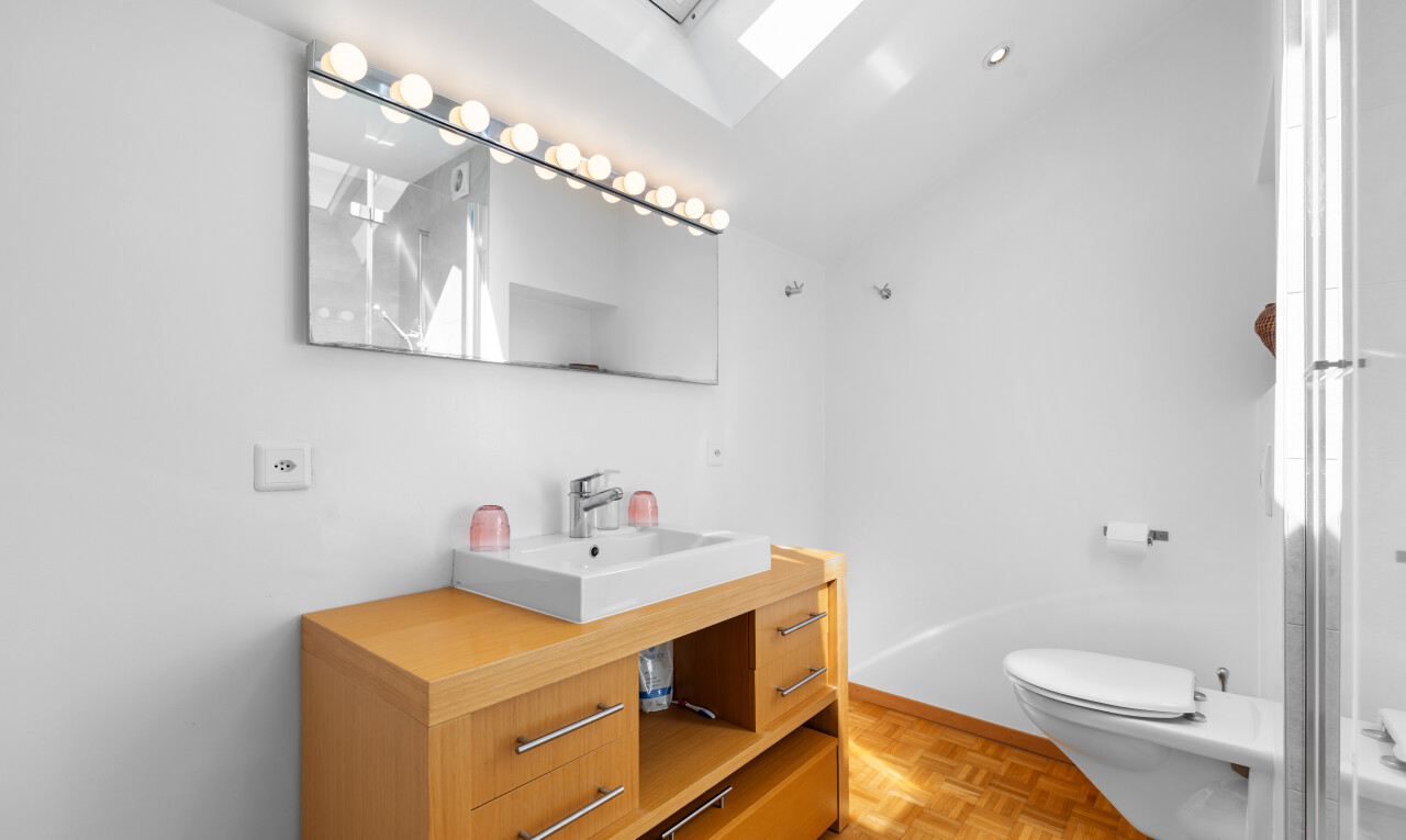 full bath featuring a skylight, vanity, parquet flooring, vaulted ceiling, and a shower with door