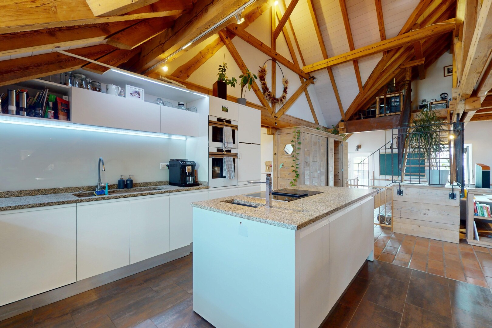 kitchen featuring white cabinetry, modern cabinets, high vaulted ceiling, a kitchen island with sink, and light stone countertops