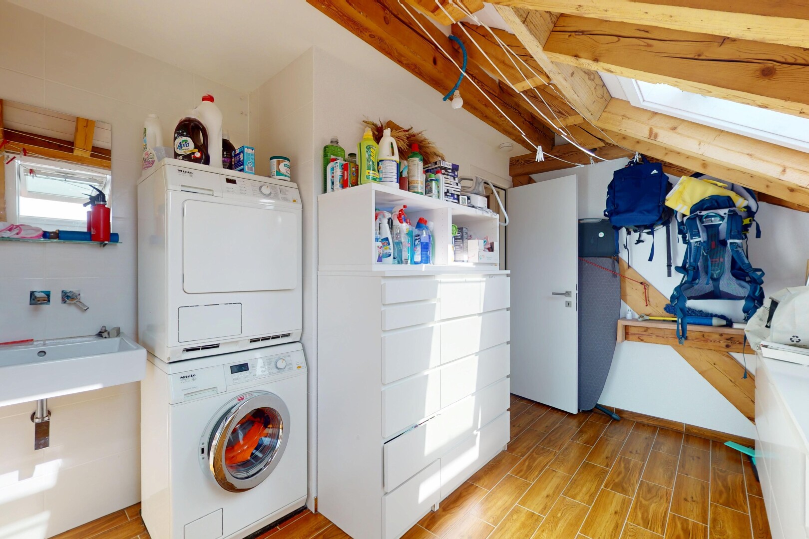 laundry room featuring estacked washer and dryer, light wood finished floors, and a skylight
