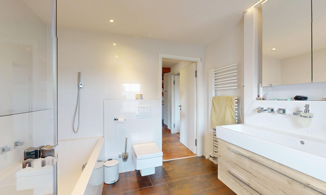 bathroom with a towel warmer, wood finished floors, vanity, a tub, and a shower