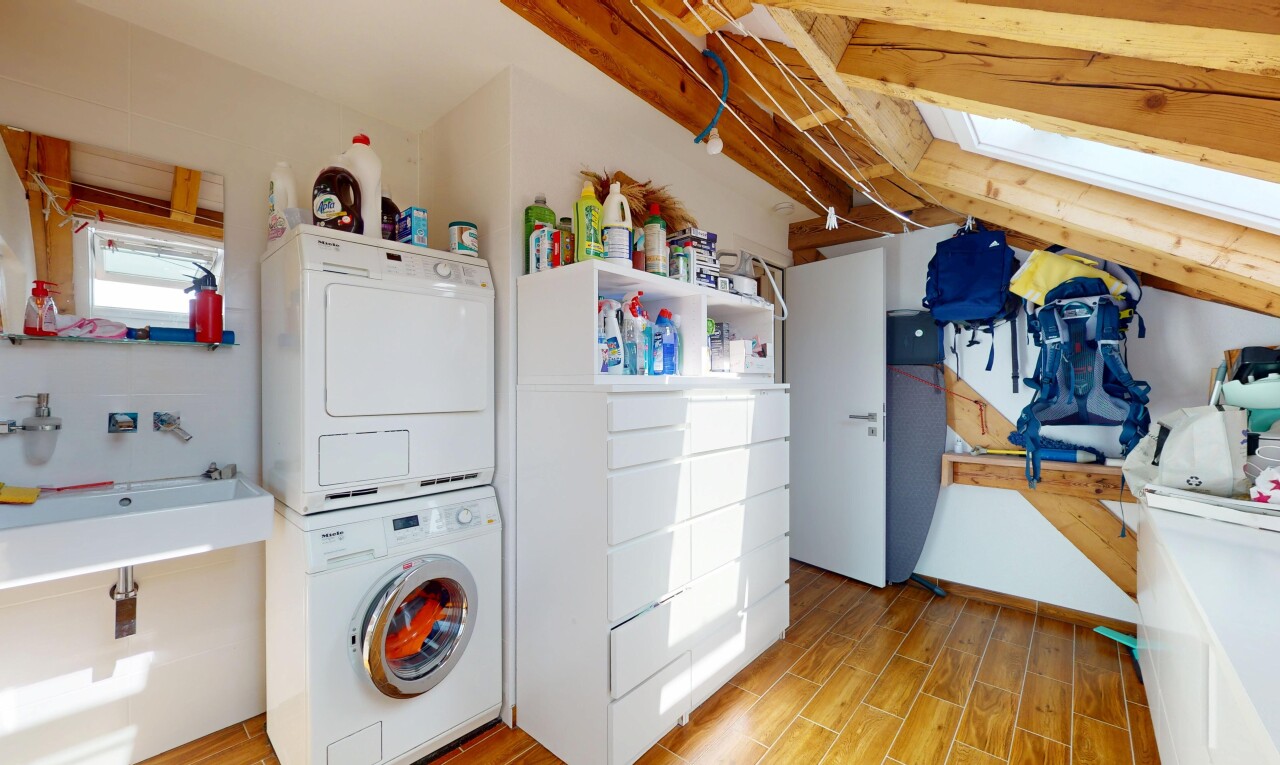 laundry room featuring estacked washer and dryer, light wood finished floors, and a skylight
