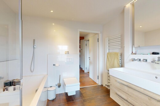 bathroom with a towel warmer, wood finished floors, vanity, a tub, and a shower