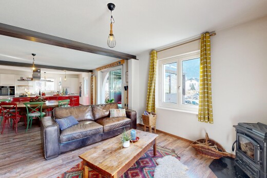 living room featuring wood finished floors, a wood stove, and beamed ceiling