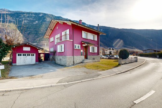 view of property featuring a mountain view, an outdoor structure, driveway, a chimney, and a garage