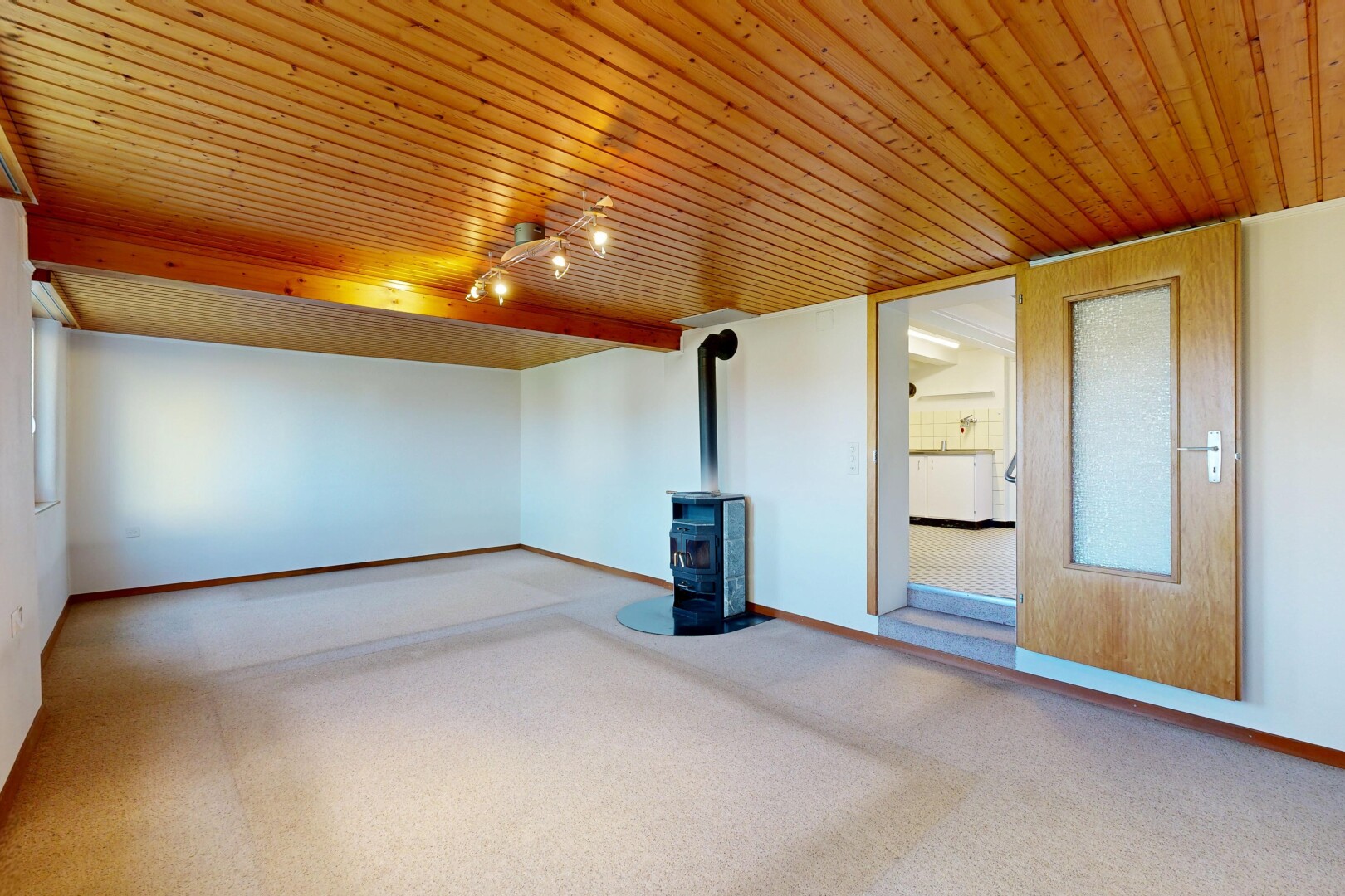 empty room with a wood stove, carpet flooring, and wood ceiling