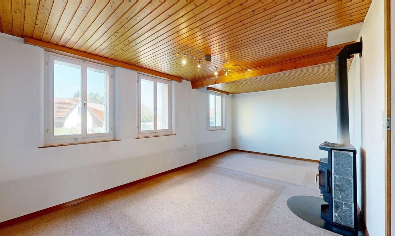 carpeted spare room featuring a wood stove and a wooden ceiling with exposed beams