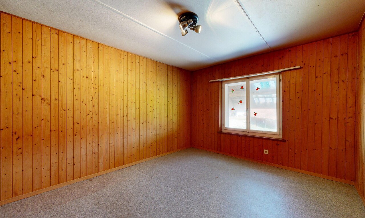 carpeted empty room featuring wooden walls