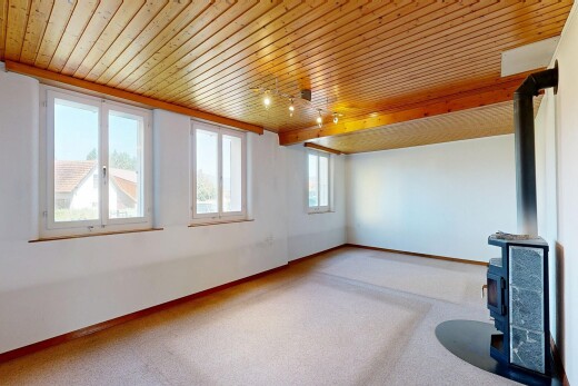 carpeted spare room featuring a wood stove and a wooden ceiling with exposed beams
