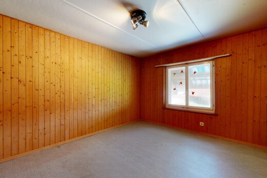 carpeted empty room featuring wooden walls