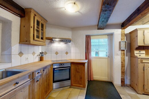 kitchen featuring stainless steel oven, decorative backsplash, a textured ceiling, glass insert cabinets, and beamed ceiling