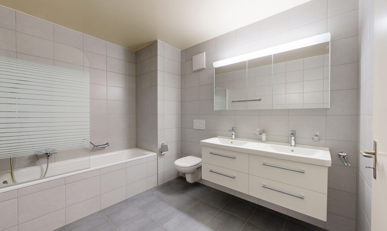 bathroom featuring tile walls, double vanity, tiled tub, and dark tile patterned floors