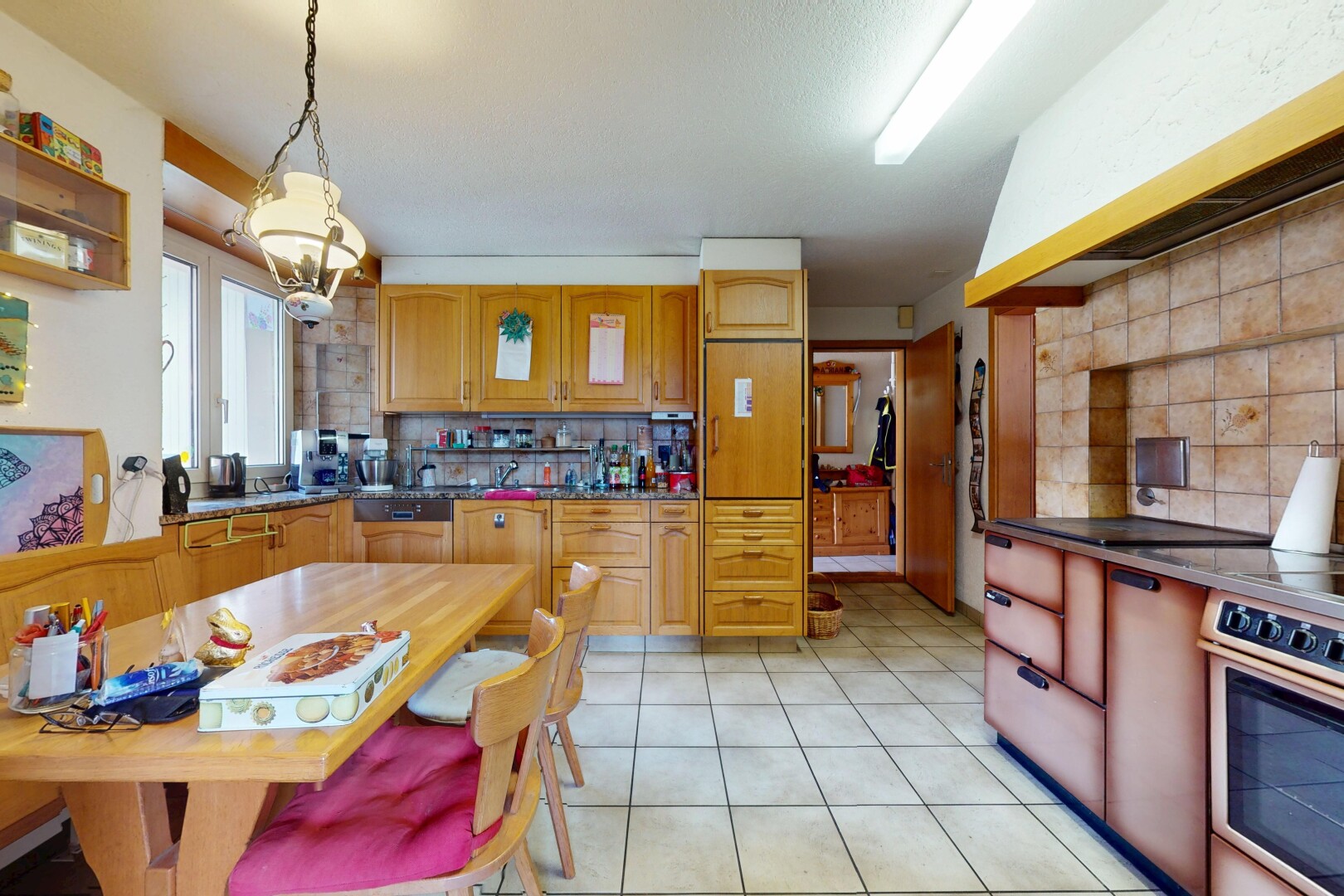 kitchen with backsplash, decorative light fixtures, light tile patterned flooring, and range hood