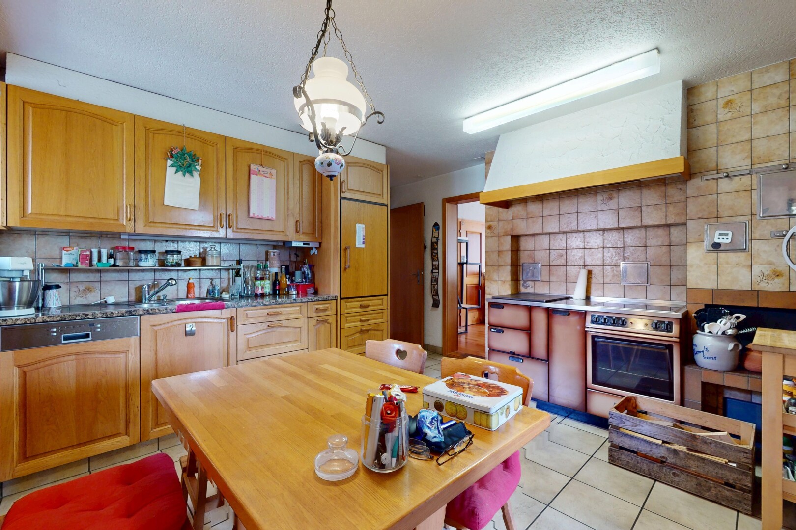 kitchen with backsplash, light tile patterned flooring, extractor fan, oven, and hanging light fixtures
