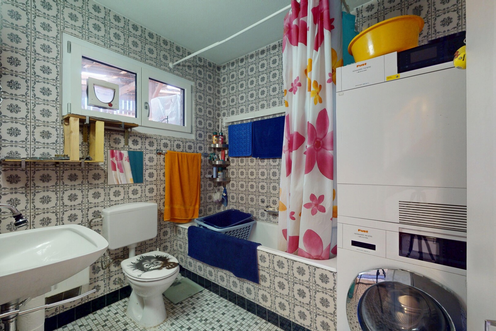 bathroom with tile patterned flooring, tiled shower / bath, stacked washer / dryer, and wallpapered walls