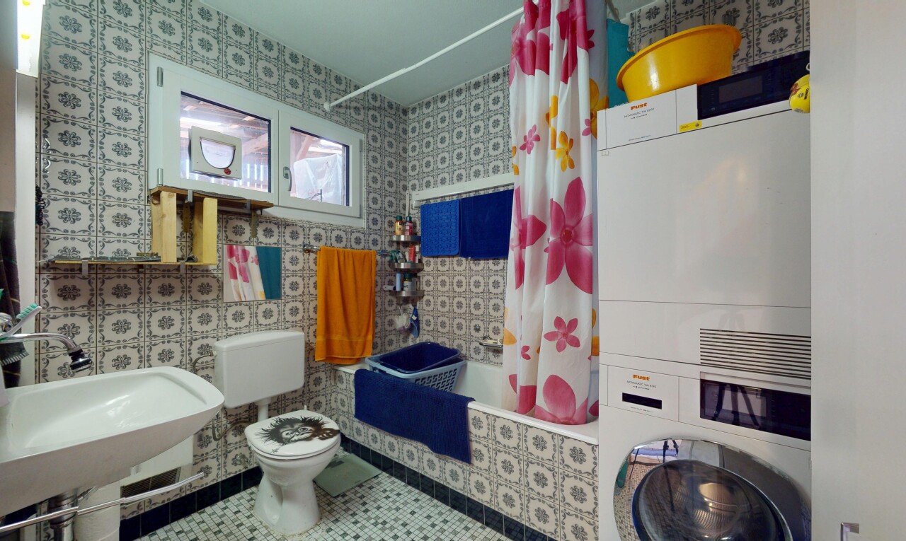 bathroom with tile patterned flooring, tiled shower / bath, stacked washer / dryer, and wallpapered walls