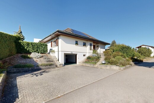 outdoor house featuring roof mounted solar panels, an attached garage, driveway, and stucco siding