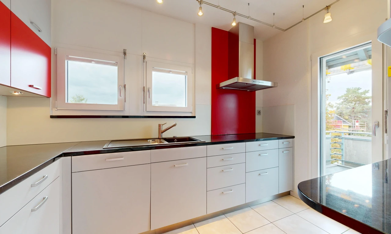 cuisine avec éclairage sur rail, hotte, dark countertops, plans de travail, et white cabinets