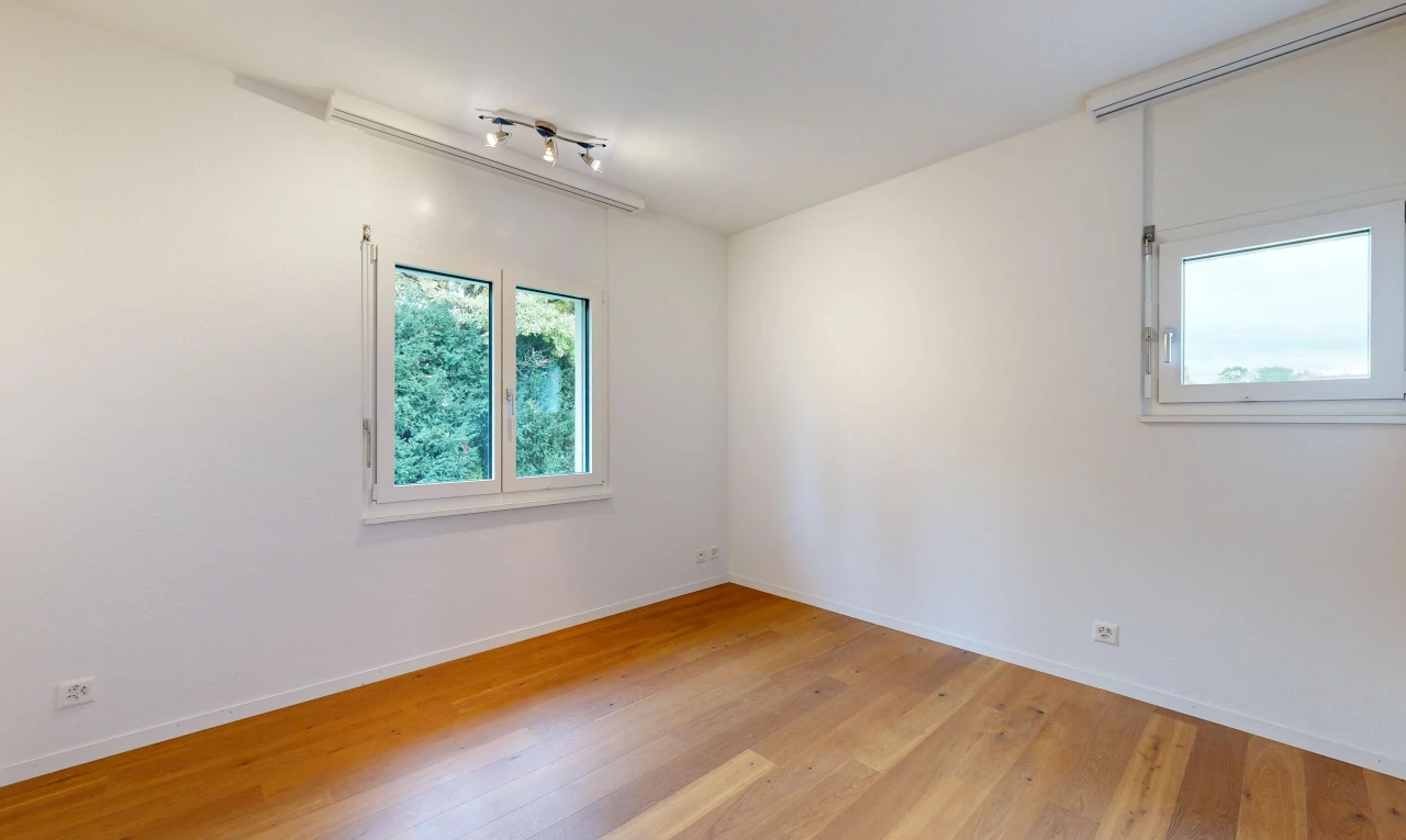 pièce vide avec éclairage sur rail, cloison sèche, drywall, sol en finition bois, et wood finish floor