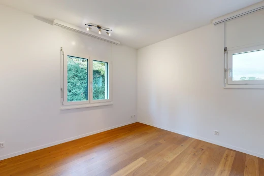 pièce vide avec éclairage sur rail, cloison sèche, drywall, sol en finition bois, et wood finish floor