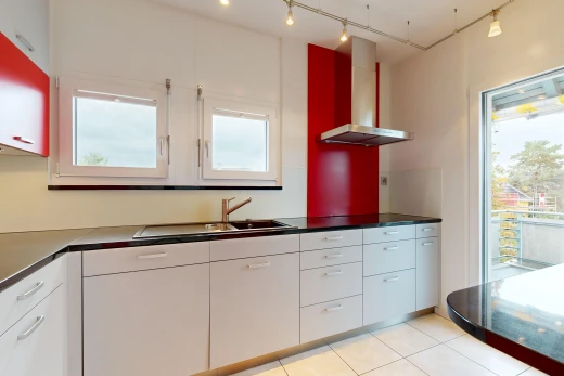 cuisine avec éclairage sur rail, hotte, dark countertops, plans de travail, et white cabinets