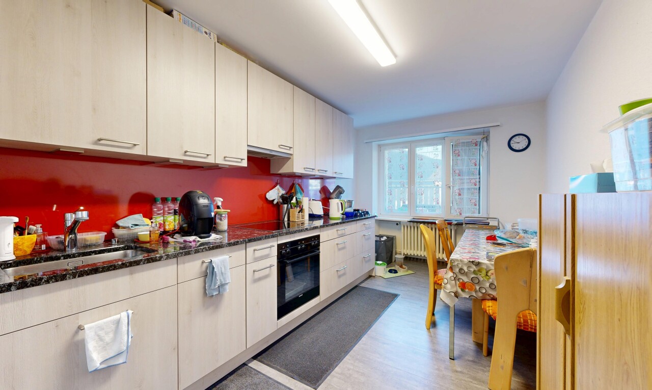 kitchen with black appliances, dark stone countertops, radiator, light wood-style flooring, and under cabinet range hood