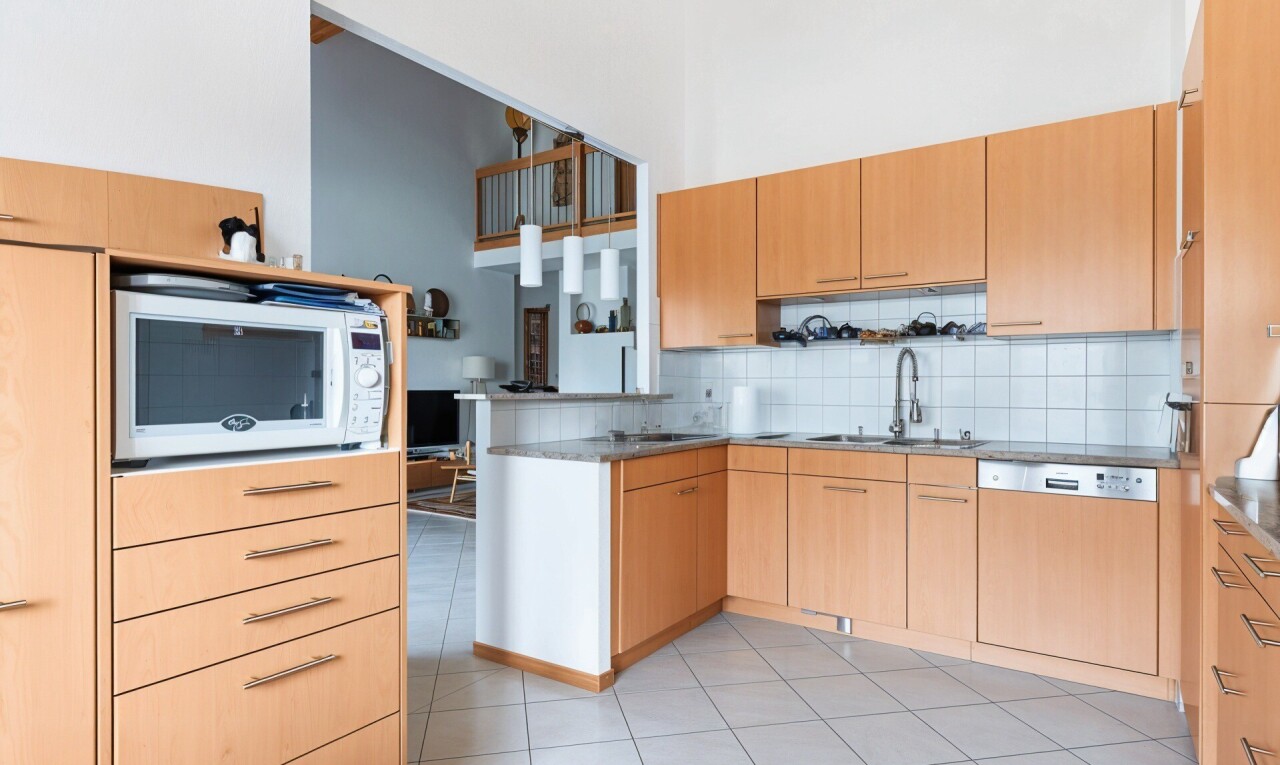 cuisine avec armoires marron clair, micro-ondes, lave-vaisselle, dosseret, et backsplash