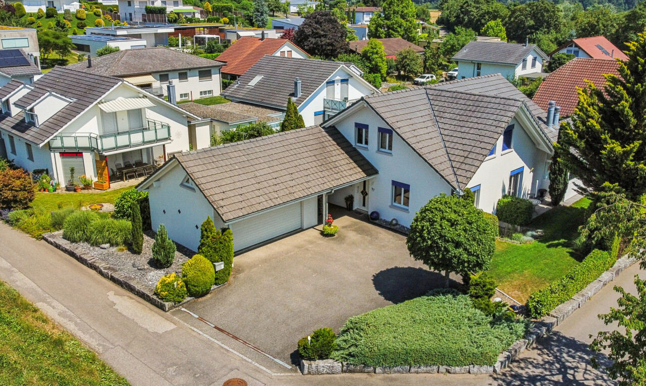 außenansicht mit auffahrt, stuckverkleidung, garage angeschlossen, property visible, und residential view