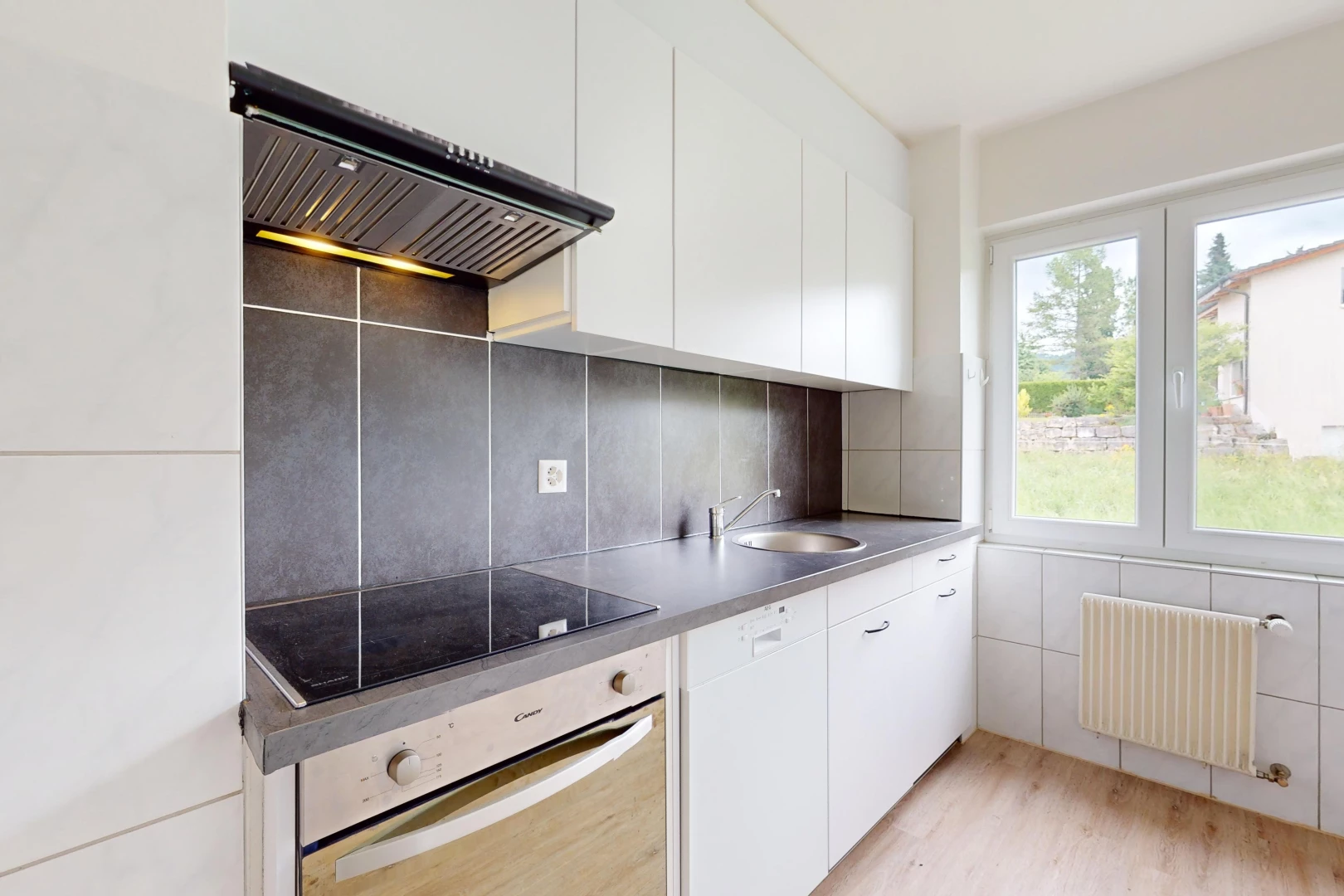 cuisine avec lumière naturelle, plancher de bois, radiateur, hotte, et four