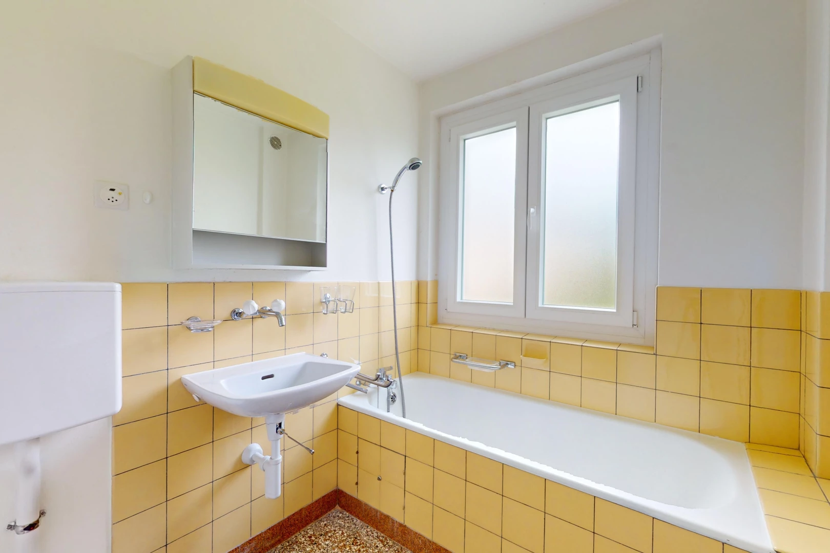 salle de bains avec miroir, mur carrelé, et lumière naturelle