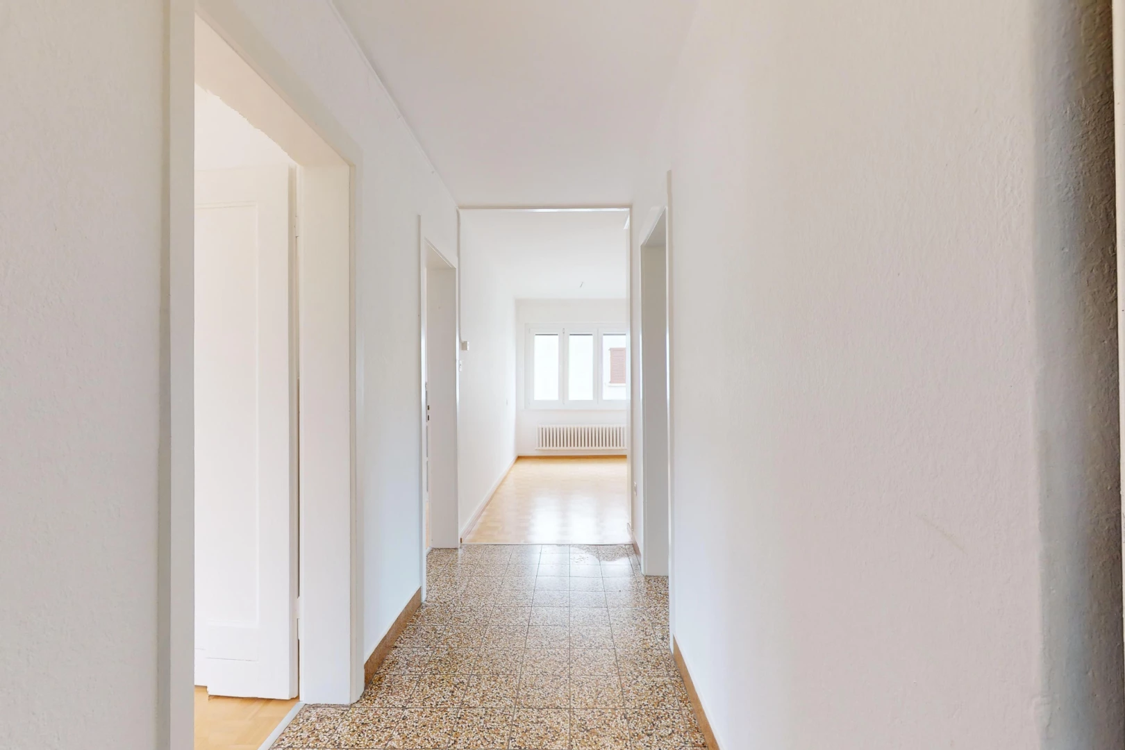 couloir avec sol en agrégat, lumière naturelle, et radiateur