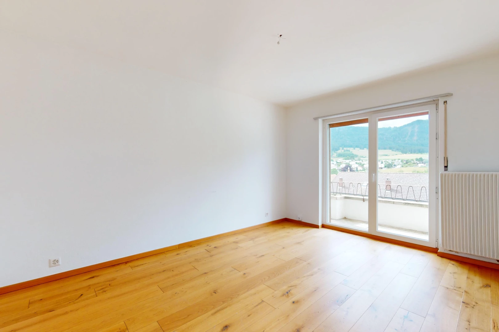 pièce vide avec plancher de bois, lumière naturelle, et radiateur