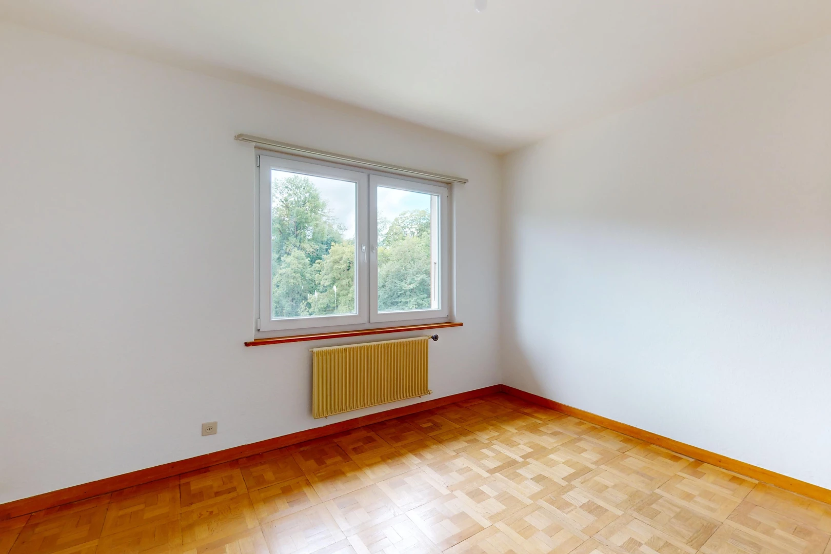 pièce vide avec radiateur, parquet, et lumière naturelle