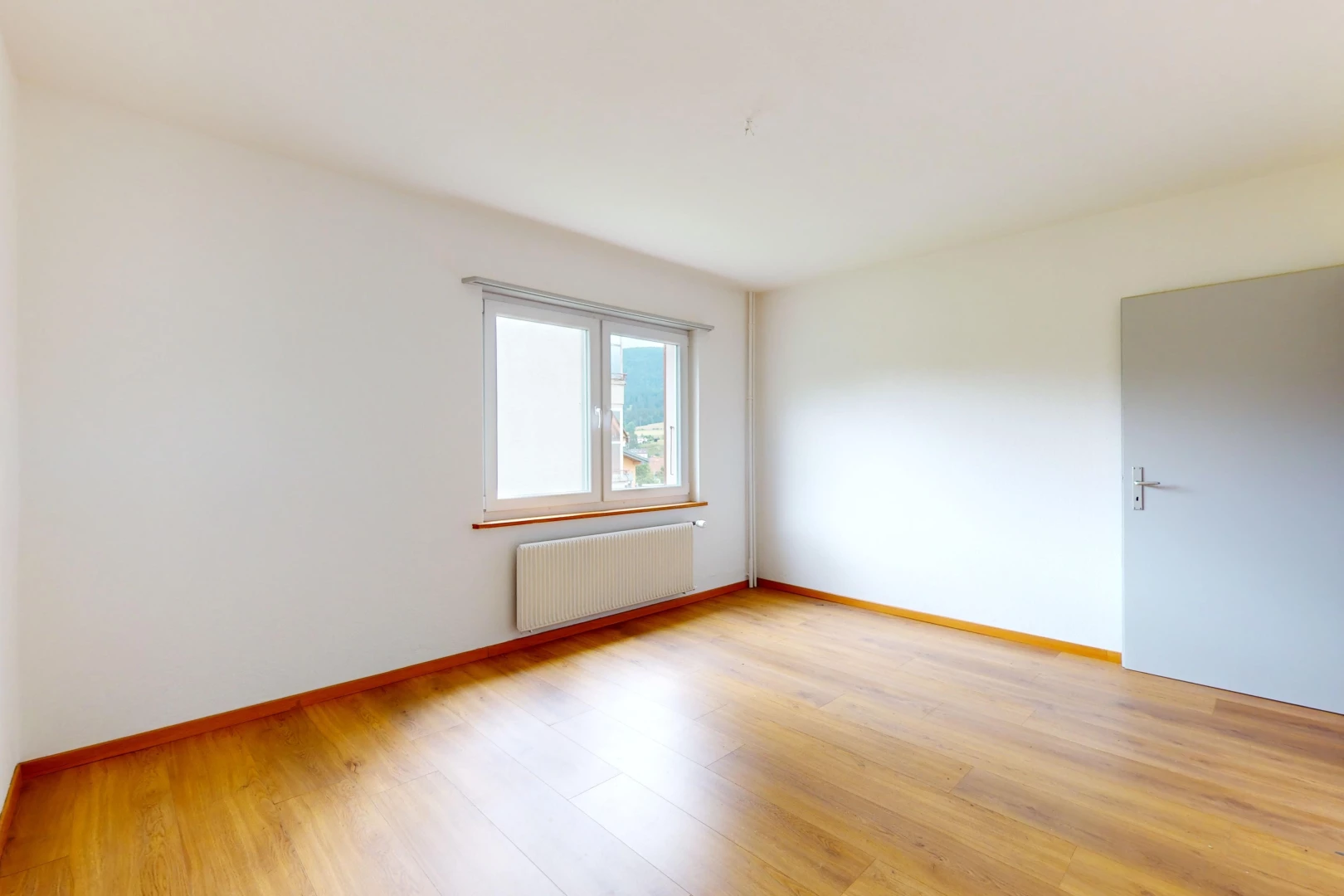 pièce vide avec radiateur, plancher de bois, et lumière naturelle