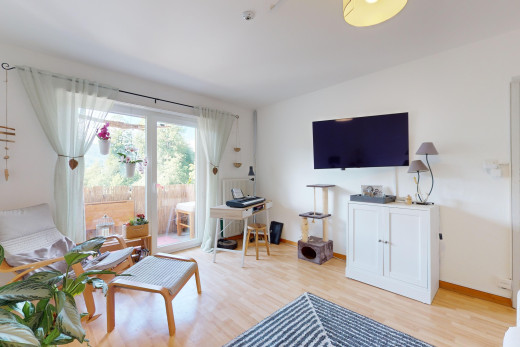 salon avec plancher de bois, télévision, et lumière naturelle