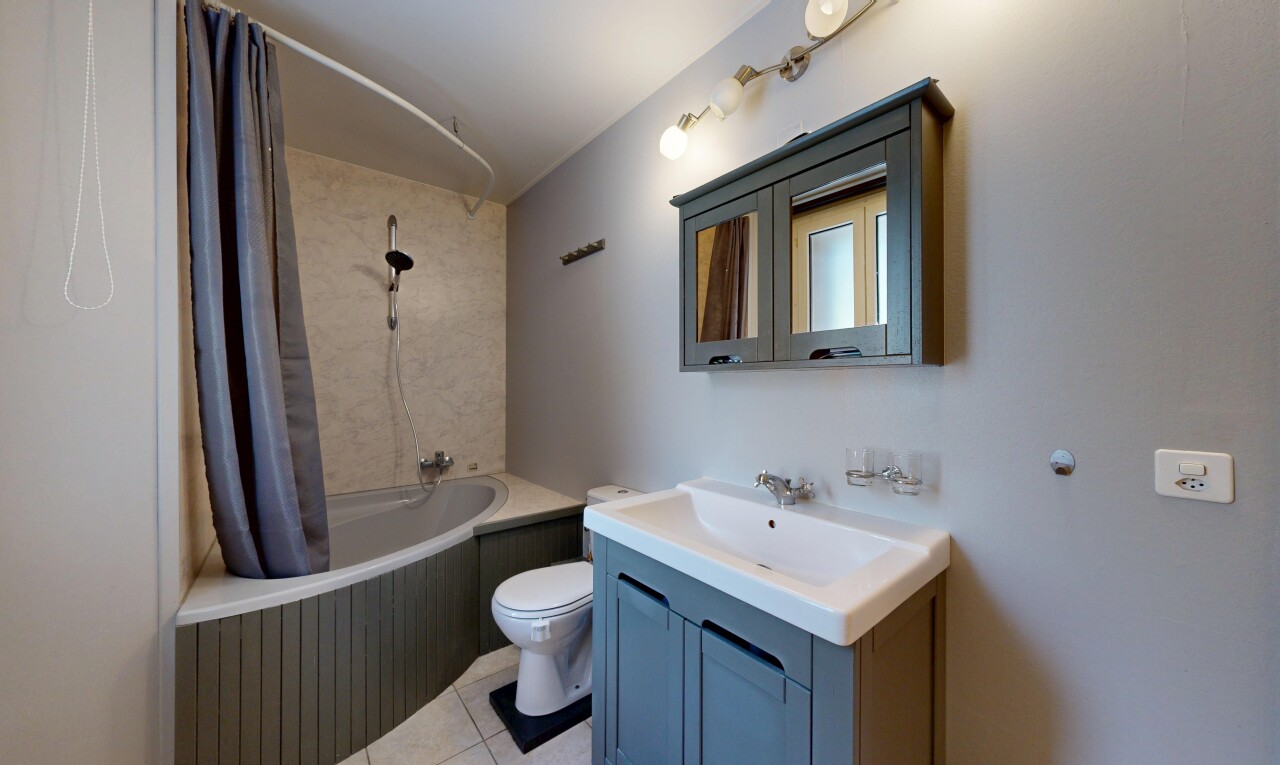 salle de bains avec miroir, lavabo (ou coiffeuse selon le contexte), salle de bain complète, douche-bain combinés, et toilette