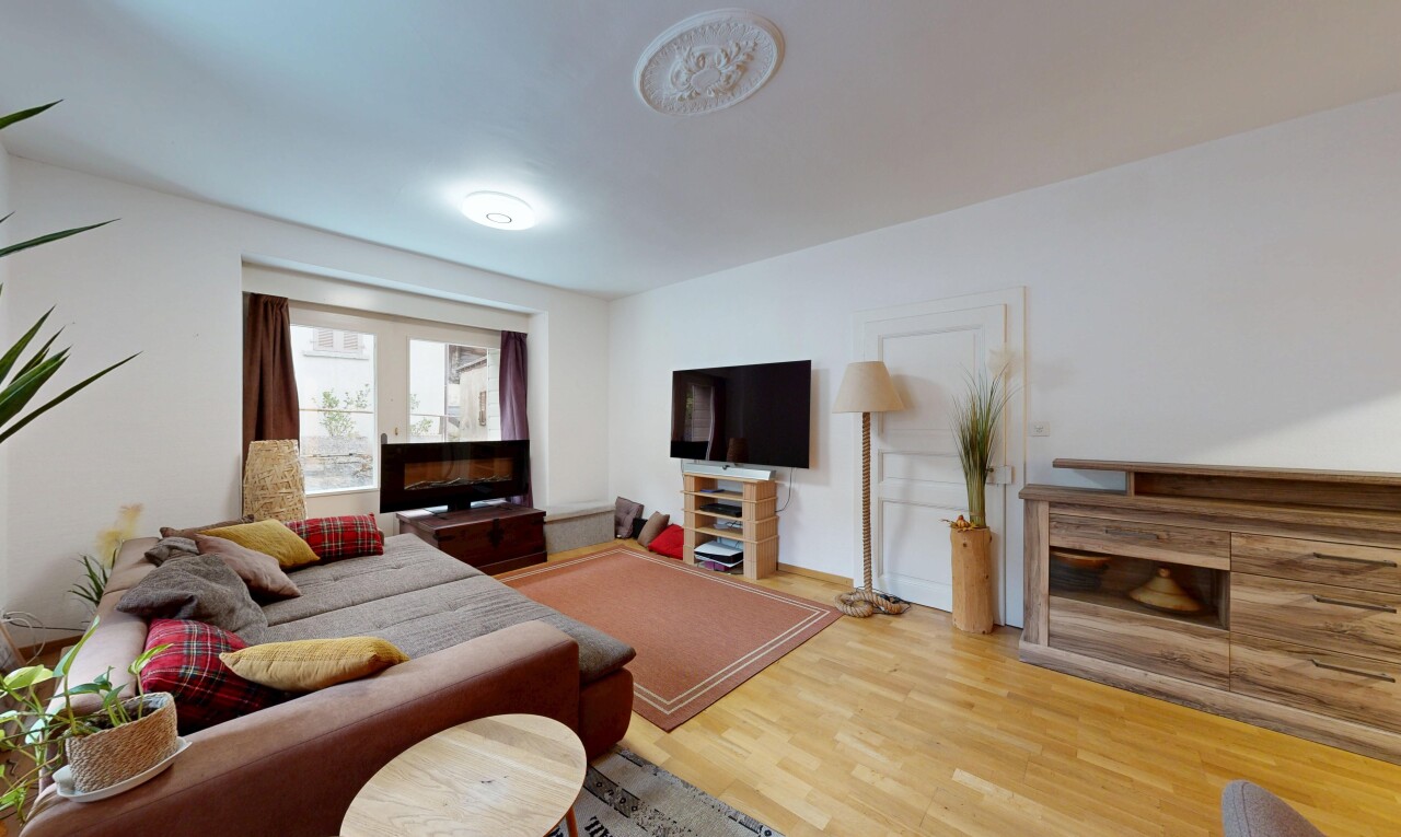 salon avec drywall, cloison sèche, cheminée, télévision, et wood finish floor