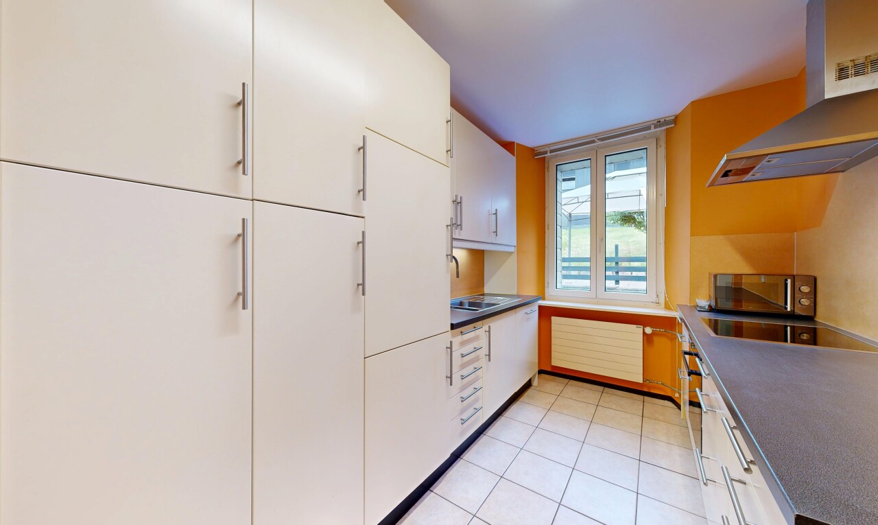 cuisine avec hotte, light floor, dark countertops, plans de travail, et lumière naturelle
