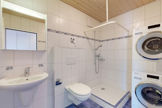 salle de bains avec tile wall, mur en carrelage, miroir, douche, et lave-linge et sèche-linge superposés