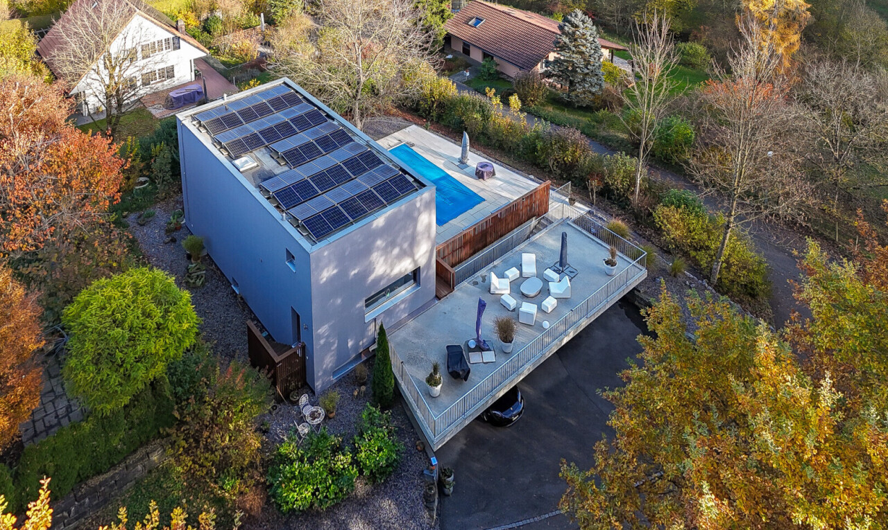 façade avec panneaux solaires, terrasse, et allée