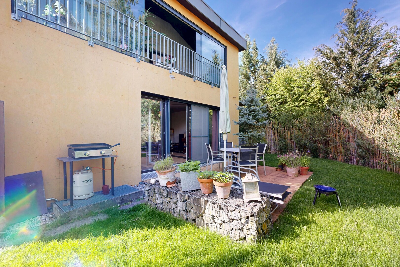 outdoor house with a patio area, stucco siding, a lawn, and a balcony