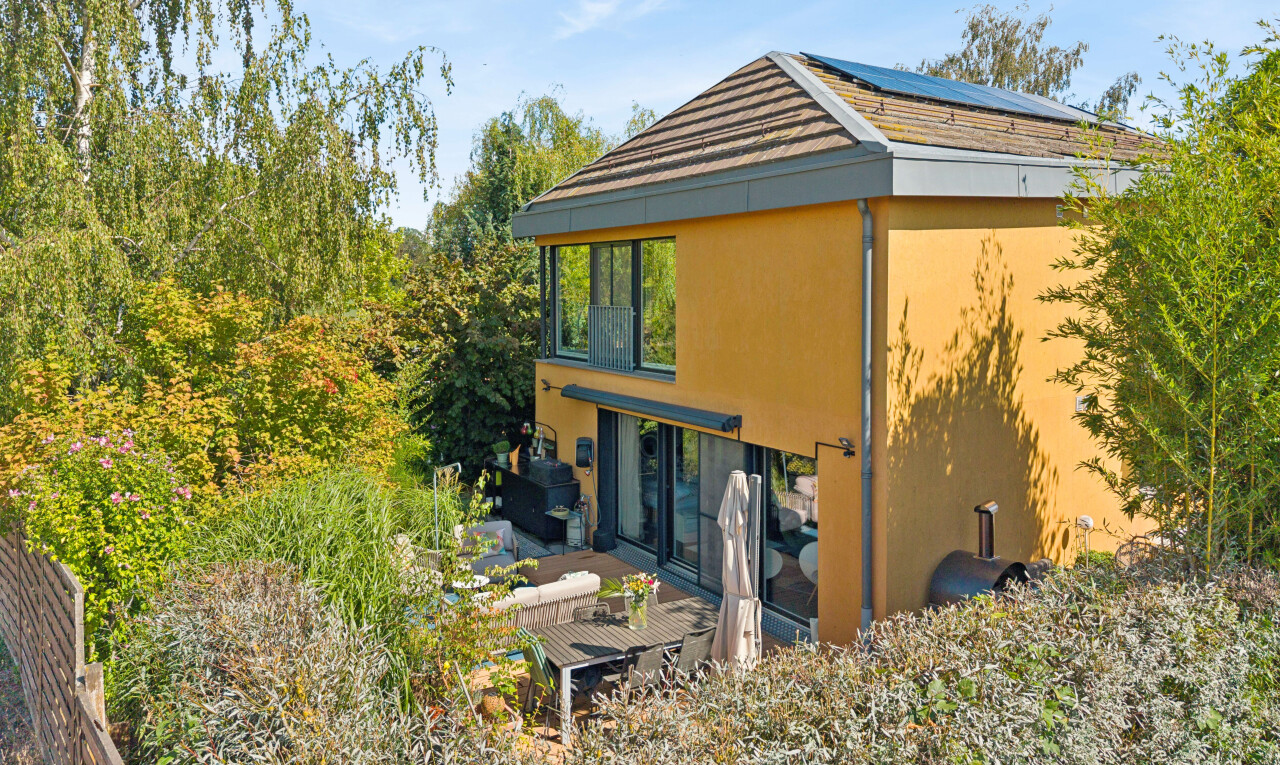 outdoor house with a wooden deck, solar panels, and stucco siding