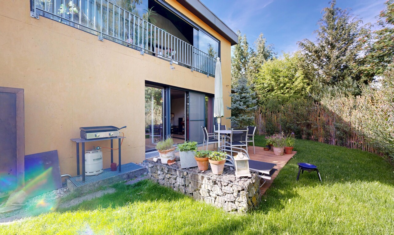 outdoor house with a patio area, stucco siding, a lawn, and a balcony