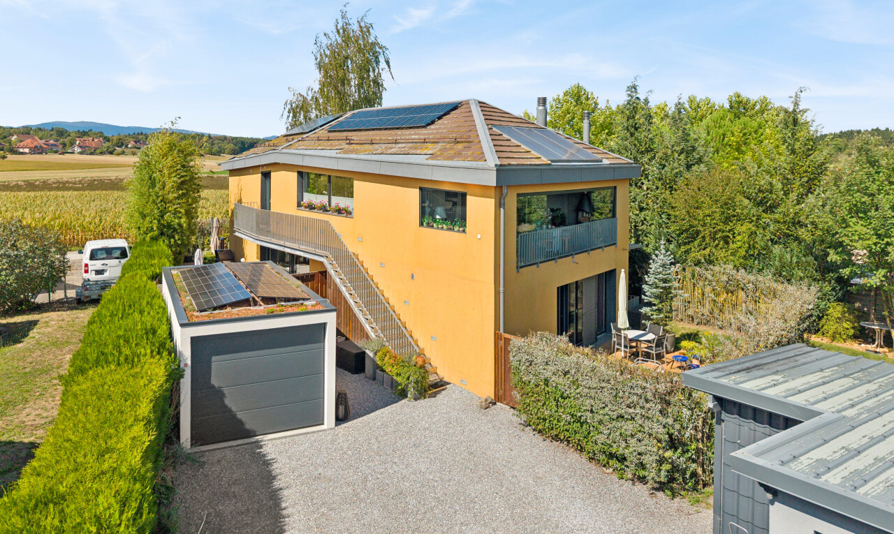 view of property featuring roof mounted solar panels, a garage, driveway, and stucco siding