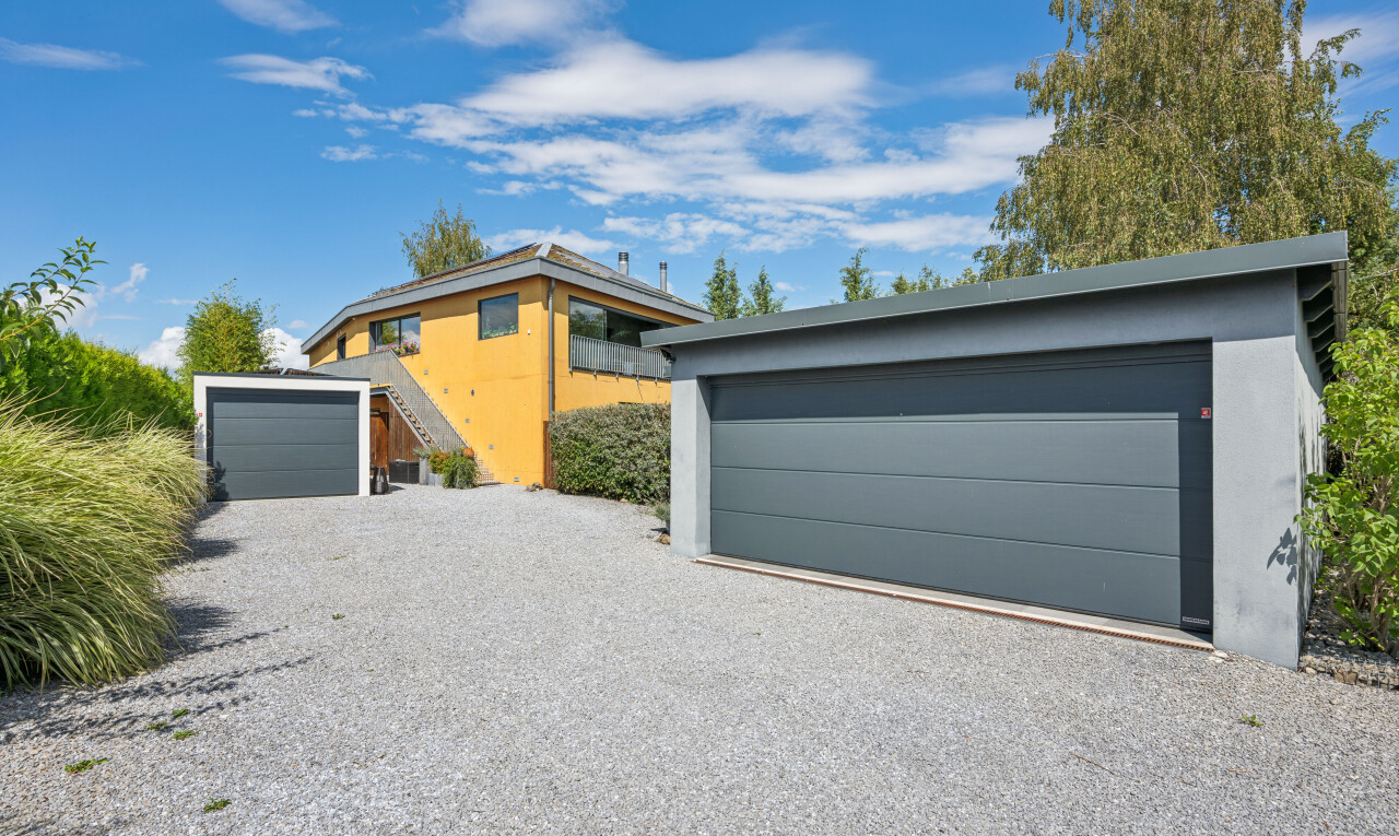 façade avec bardage en stuc, day time, garage détaché, property visible, et allée