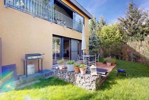 outdoor house with a patio area, stucco siding, a lawn, and a balcony