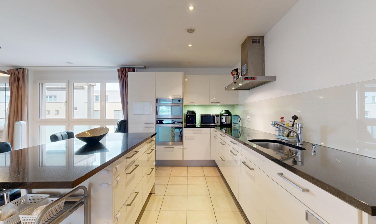 cuisine avec hotte, dark countertops, light floor, stone countertops, et plans de travail en pierre